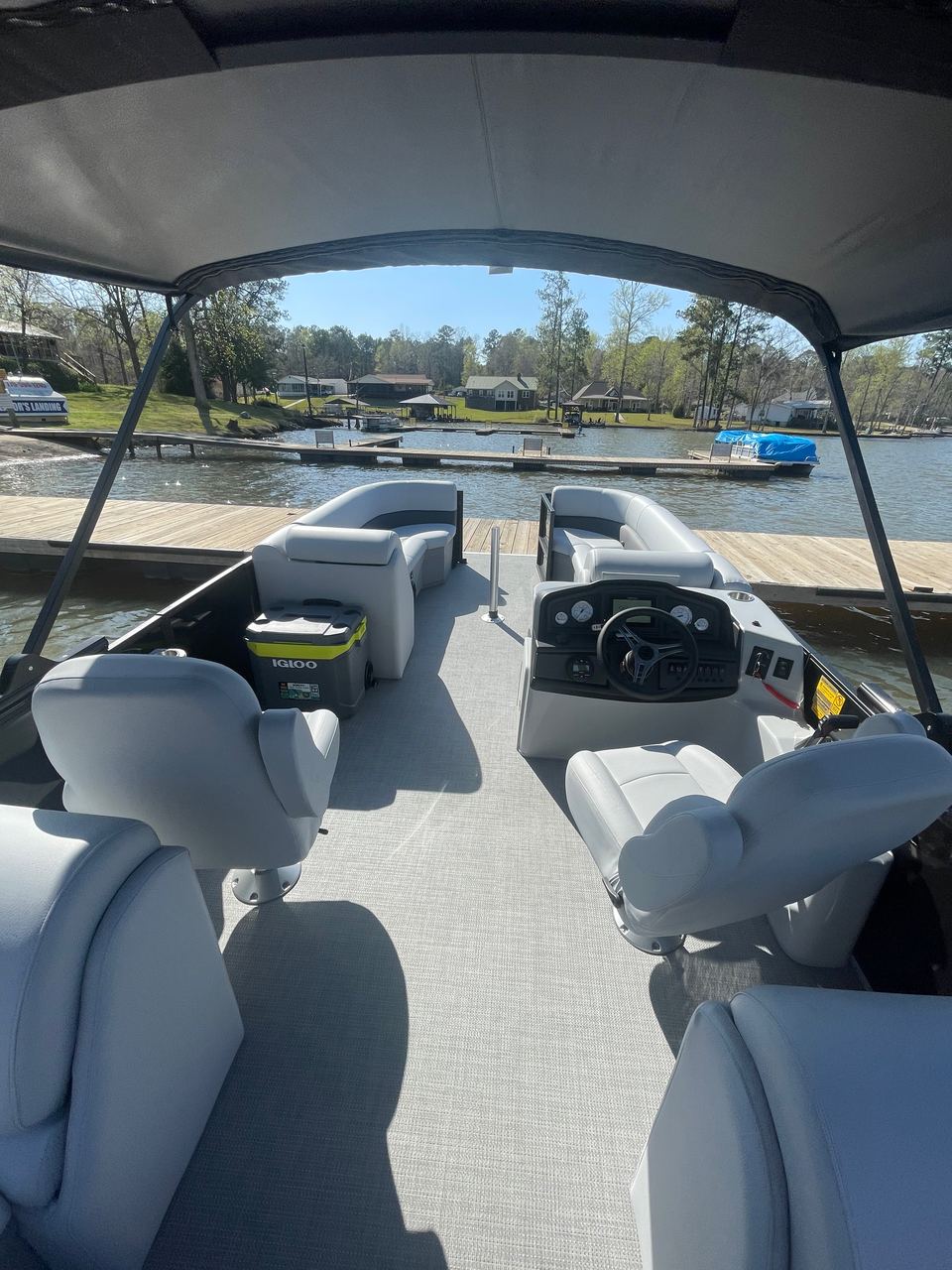 Bentley Navigator 243 deck under the bimini top: gray seats, helm and a cooler